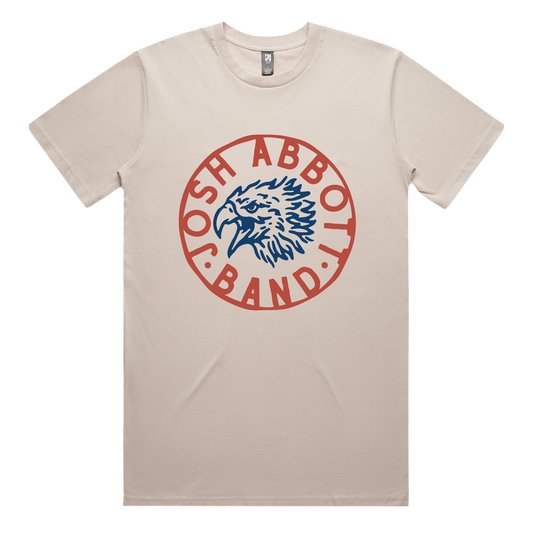 Beige t-shirt featuring a circular red logo with an eagle head design and text.